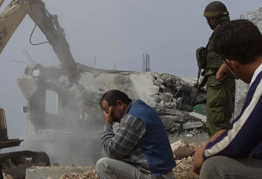 İsrail tarafından ruhsatsız olduğu gerekçesiyle evleri yıkılan Filistinliler.