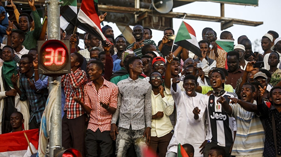 Hartum'daki ordu karargahının dışında toplanan Sudanlı gençler ulusal bayrakları dalgalandırıp, sevinç sloganları attı.