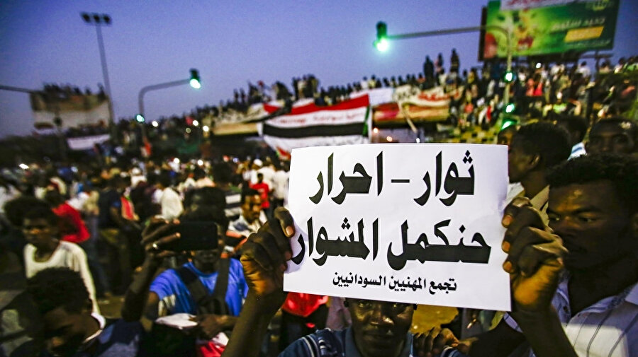 Sivil geçiş hükümeti talep eden Sudanlı protestocular. Pankartta "Devrimciler özgür yola devam" yazıyor.