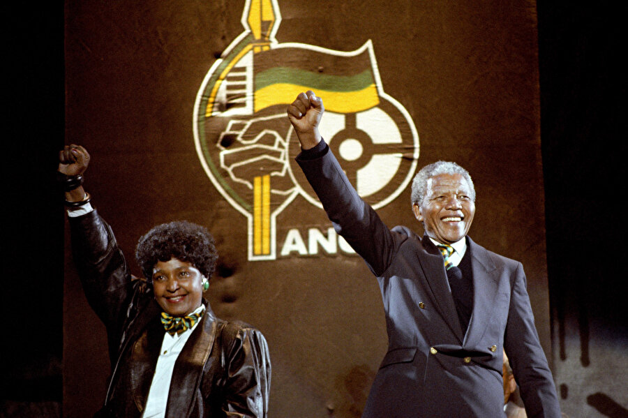 Nelson Mandela, o zamanki eşi Winnie ile 17 Nisan 1990'da Londra'daki Wembley Stadyumu'ndaki konserde Afrika Ulusal Kongresi’nin meşhur selamı sıkı yumrukla insanları selamlıyor.