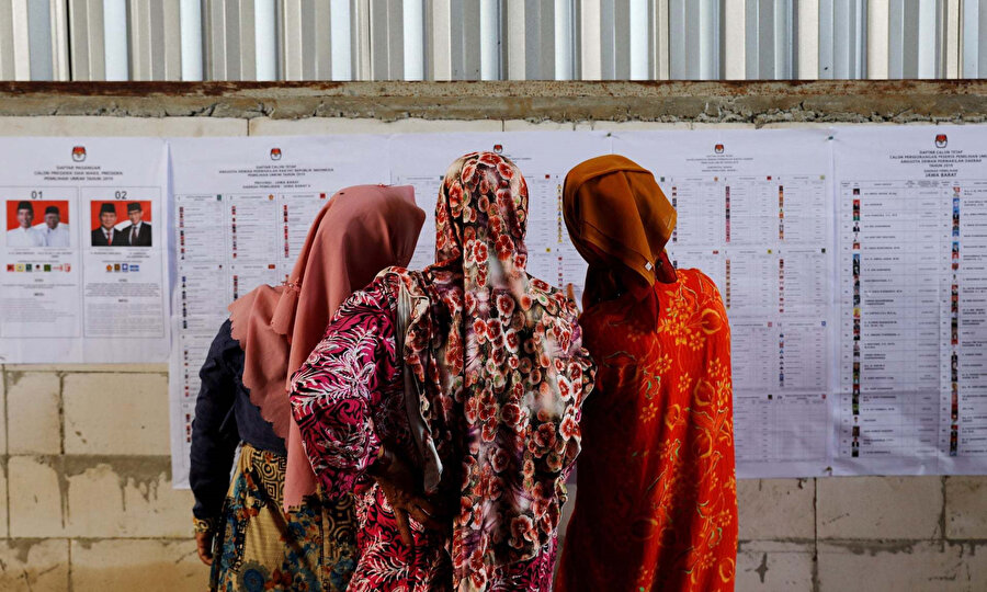 Kadınlar, Endonezya'daki seçimler için oy kullanma bilgilerine bakıyorlar.