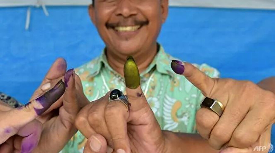 Endonezyalı erkek seçmenler Tangerang'daki bölgesel seçimler sırasında oy kullandıktan sonra parmaklarını gösteriyorlar.