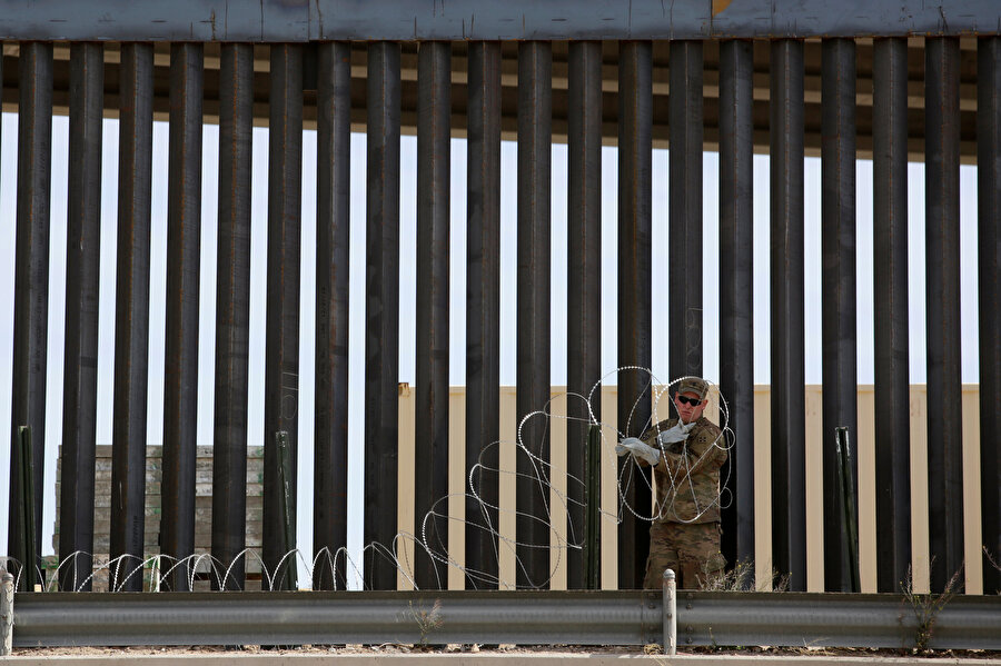 ABD'li bir asker, Meksika ve ABD arasındaki sınır tellerinin yanında görünüyor.