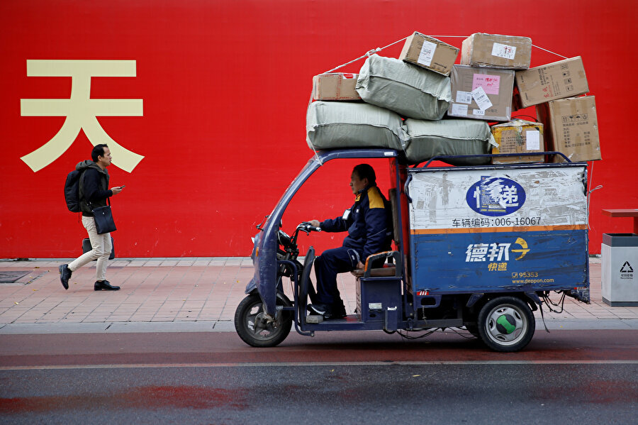Elektrikli bisikletiyle yük taşıyan bir Çinli.