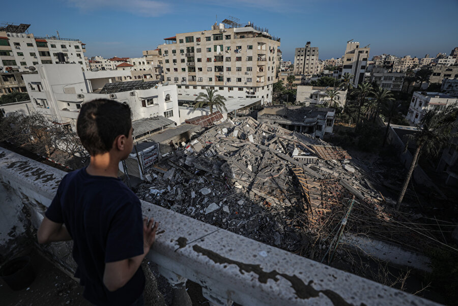 Yıkılan binanın enkazına bakan Filistinli bir çocuk.