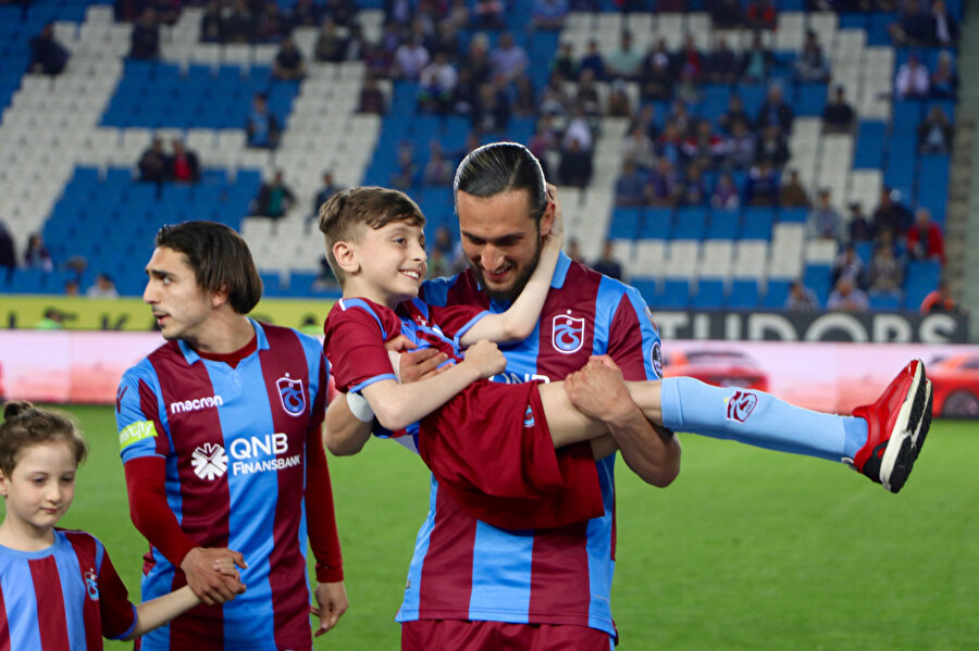 Yusuf Yazıcı, minik bir Trabzonspor taraftarını kucağında taşıyor.