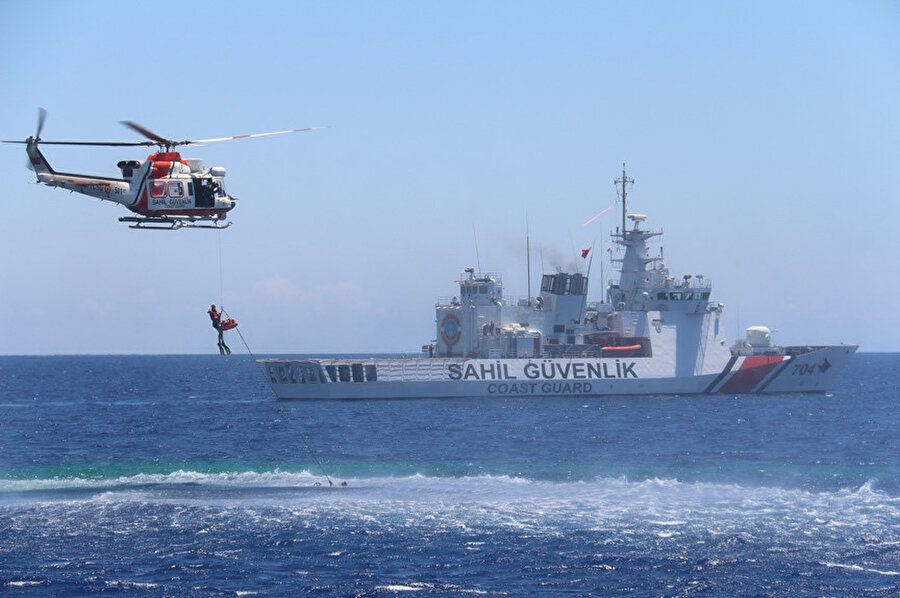 Arana-kurtarma tatbikatında sahil güvenlik gemisi ve bir helikopter görünüyor. 