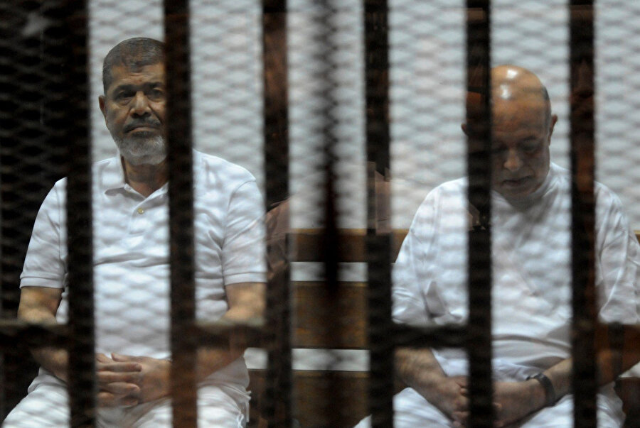 Mısır’ın eski cumhurbaşkanı Muhammed Mursi ve başkan yardımcısı Rafa el-Tahtavi, 14 Ekim 2014’te Kahire’deki polis akademisindeki duruşma sırasında sanıkların bulunduğu kafeste oturuyor.