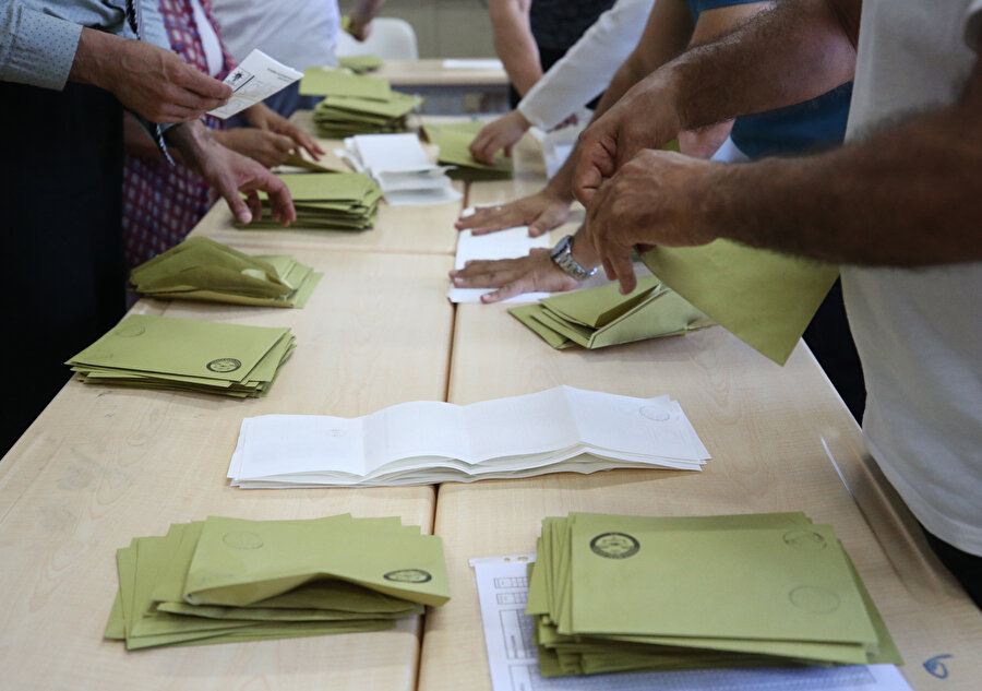 Oy sayım işlemi sırasında sandık görevlileri görülüyor.