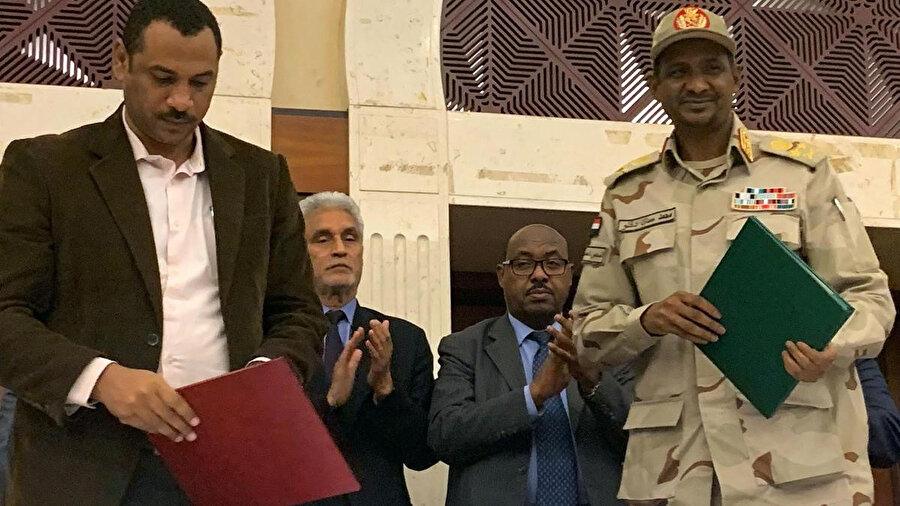 Askeri Geçiş Konseyi'nden Başkan Yardımcısı Muhammed Hamdan Dakalu (sağda), Muhalefeti temsilen Özgürlük ve Değişim Bildirgesi Güçlerinden Ahmet er-Rabi anlaşmayı imzaladıktan sonra basına poz veriyor. Hartum, Sudan.