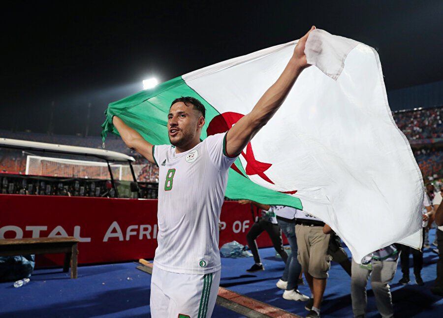 Cezayir forması giyen Youcef Belaili ülkesinin bayrağını dalgalandırıyor.