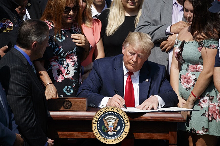 Donald Trump bir anlaşmayı imzalarken görünüyor.