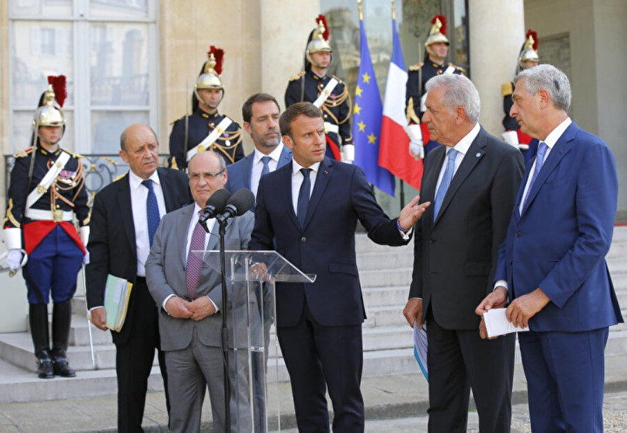 Soldan sağa, Fransa Dışişleri Bakanı Jean-Yves Le Drian, Birleşmiş Milletler Göç Dairesi Başkanı Antonio Manuel de Carvalho Ferreira Vitorino, Fransa İçişleri Bakanı Christophe Castaner, Fransa Cumhurbaşkanı Emmanuel Macron, Avrupa Göç ve İçişleri Komiseri Dimitris Avramopoulos ve United Milletler Mülteciler Yüksek Komiserliği (BMMYK) Filippo Grandi