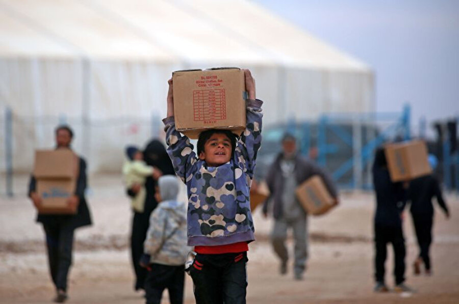 Haseke mülteci kampında yaşayan Suriyeli çocuk, UNICEF tarafından dağıtılan insani yardım paketini ailesine götürüyor.