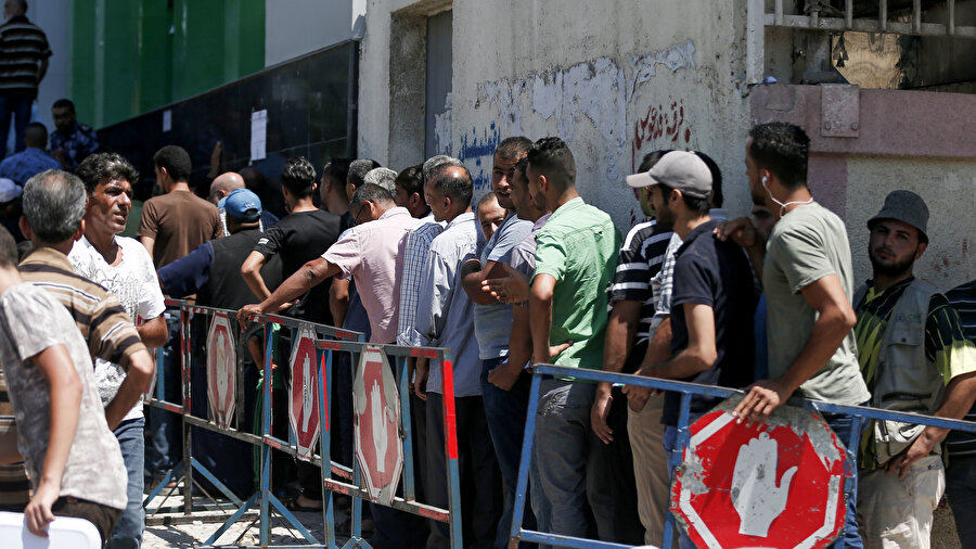 İsrail ablukası nedeniyle ekonomik dar boğazda olan, İki kişiden birinin işsiz olduğu Gazze'de, Katar'dan gelen nakit yardımı alabilmek için postane önünde sıra bekleyen Gazzeliler.