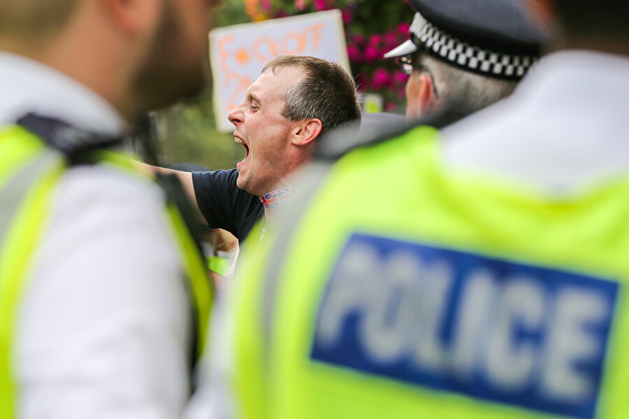 Bir gösterici polislerin önünde bağırırken görünüyor.