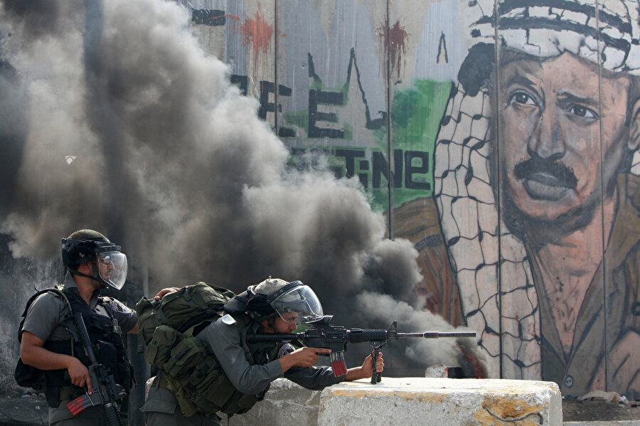 Taş fırlatan Filistinliler karşısında kontrol noktasında mevzilenen İsrail askerleri.