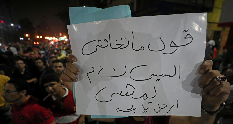 Cuma günü Cumhurbaşkanı Sisi'yi protesto etmek için toplanan Mısırlılardan biri "Korkma söyle! Sisi mutlaka gitmeli" yazan pankartı kameraya tutarken görülüyor.