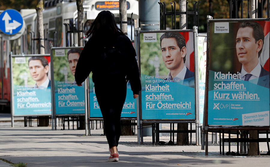 Viyana Halk Partisi (OeVP) Başkanı ve eski Şansölye Sebastian Kurz'un seçim kampanya afişlerinin önünden bir vatandaş yürürken görünüyor.