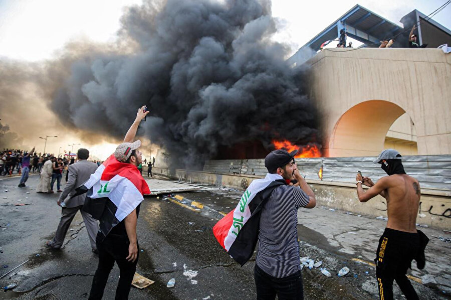 Protestocular, başkent Bağdat'ın Tahrir Meydanı ile yüksek güvenlikli Yeşil Bölge arasında yanan bir binanın yanında Irak polisi ile çatışırken görülüyor.