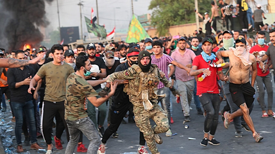 Hükümet karşıtı protestocular, bazı göstericiler tarafından dövülen Özel Kuvvetlere bağlı bir askerin, protestoların gerçekleştiği alandan çıkmasına yardım ediyor.