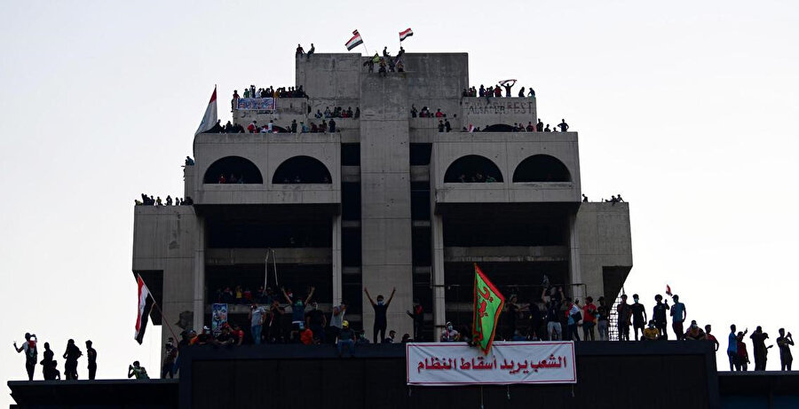 Göstericilerin yüksek bir binaya astığı pankartta "Halk rejimi devirmek istiyor" yazılı.