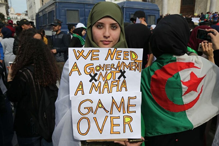 Cumhurbaşkanı Abdulaziz Buteflika karşıtı gösterilerde üzerinde "Mafya iktidarına değil, hükumete ihtiyacımız var. Oyun bitti" yazılı pankart taşıyan bir gösterici. 
