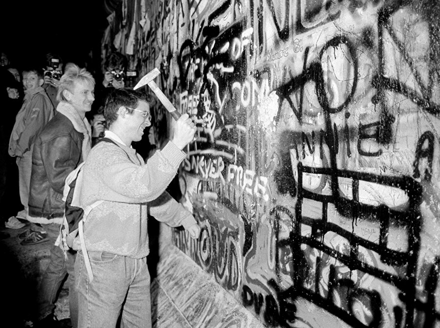 Bir vatandaş, Berlin Duvarı'nın bir bölümünü kırarken görünüyor.