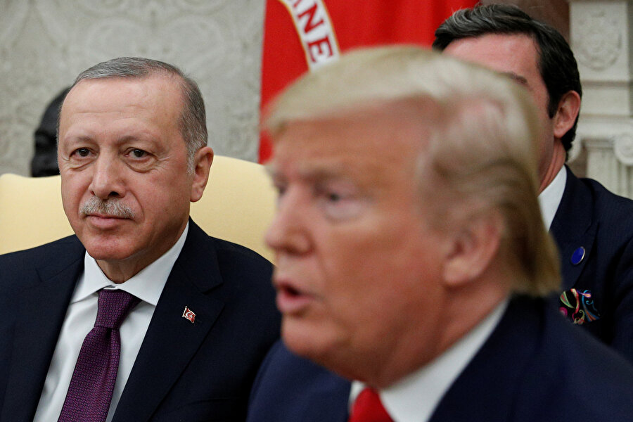 Cumhurbaşkanı Erdoğan, Trump konuşurken kameralara poz veriyor.