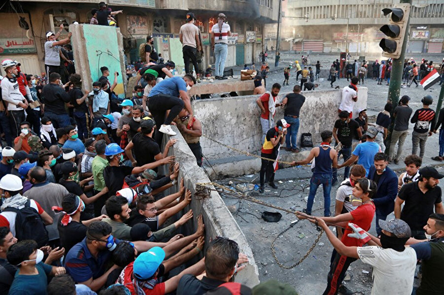 Irak’ın başkenti Bağdat’ta göstericiler, Tahrir Meydanı yakınlarındaki Hıllani Meydanı'ndaki beton blokları kaldırmaya çalışırken görülüyor.