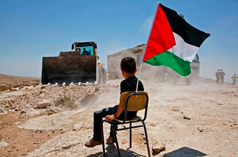 Batı Şeria'da okul bölgesinde yıkım gerçekleştiren İsrail güçlerini izleyen Filistinli bir çocuk.