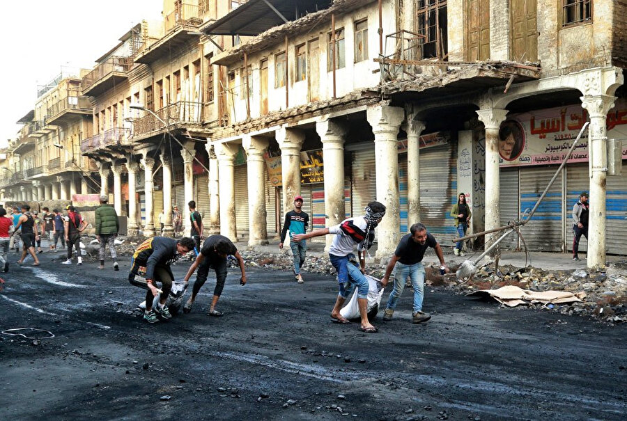 Göstericiler, polisle çıkan çatışmalar esnasında zarar gören ve kirlenen caddeleri temizledi.