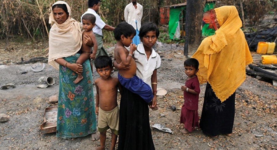 2016 yılında çekilen bu fotoğrafta, Myanmar'da yaşayan Arakanlı Müslümanlar köylerinde ateşe verilen bakkalın yanında dururken görülüyor. 