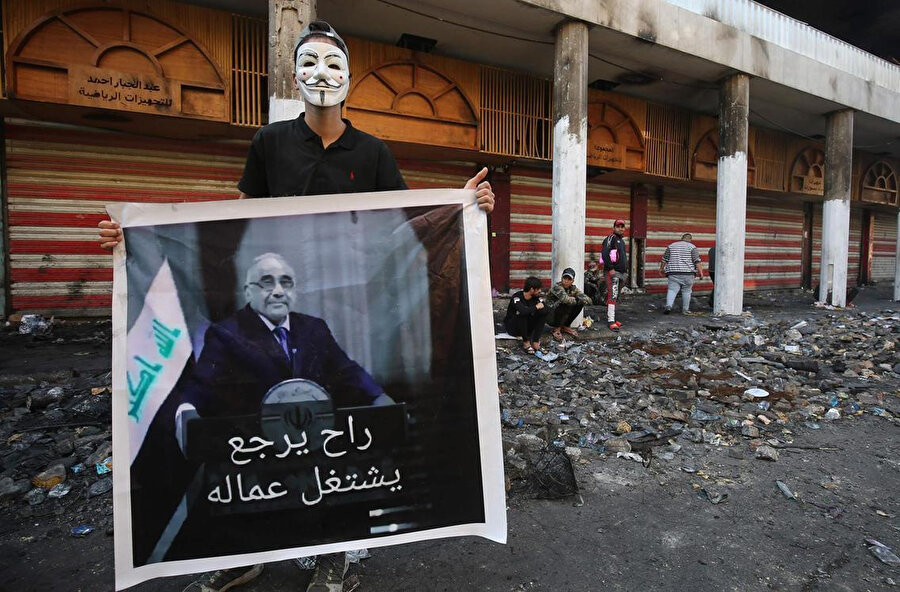Irak'ta bir gösterici protestolar sonrası istifa eden Başbakan Abdulmehdi'nin posteriyle.
