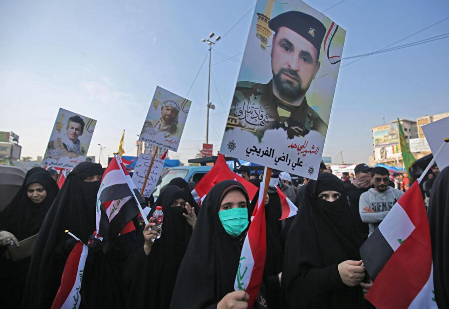 Tahrir Meydanı'ndaki protestolar sırasında çatışmalarda ölen Haşdi Şabi militanlarının posterlerini taşıyan göstericiler.