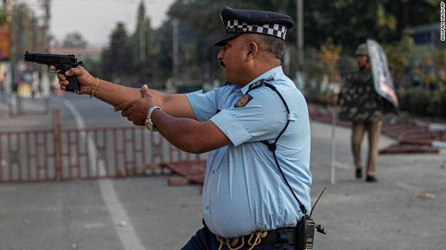 Taş atan göstericileri hedef almaya hazırlanan bir Hint polisi.