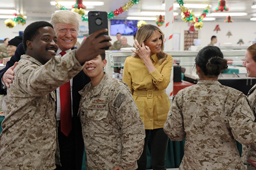 Donald Trump ve eşi Melania Trump askerlerle fotoğraf çektirirken görünüyor.