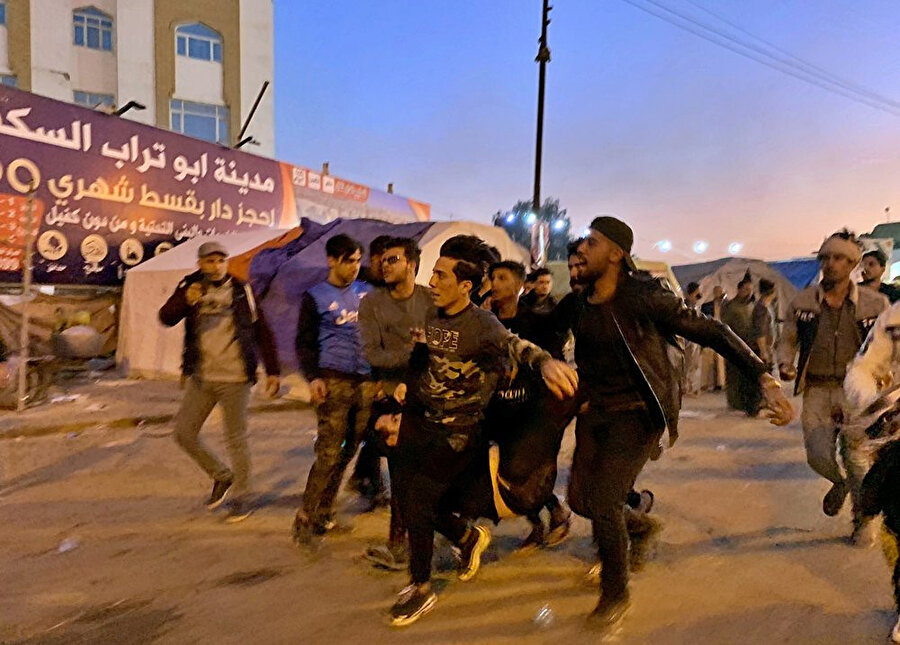Sadr'a bağlı kişilerin açtığı ateş sonucu yaralanan bir gösterici Necef'teki hastaneye yetiştirilmeye çalışılıyor.