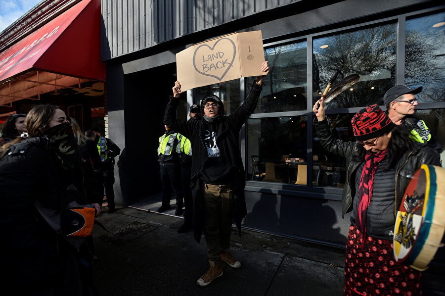 Bir gösterici, "Arazimizi geri istiyoruz" yazan bir döviz taşıyor