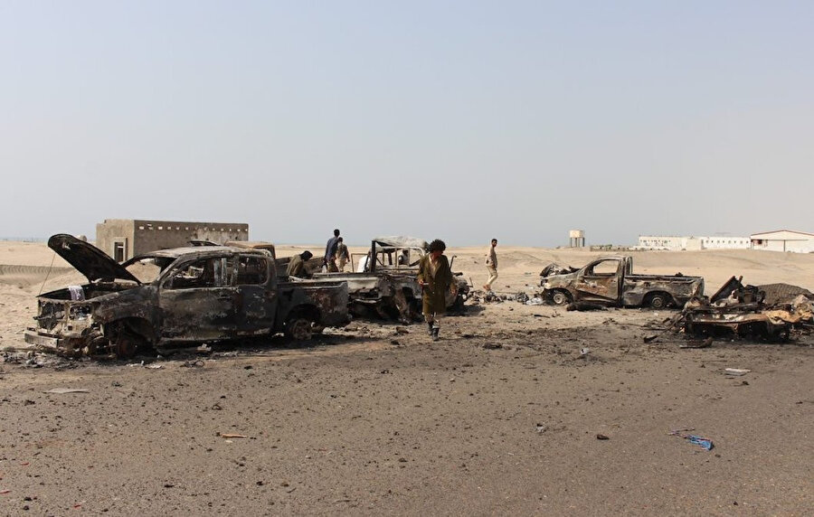 Yemenli savaşçılar, Yemen'in geçici başkenti Aden'de BAE 'nin hava saldırılarının ardından hükümet yanlısı birliklere ait olduğu bildirilen yanmış araçları inceliyor. 