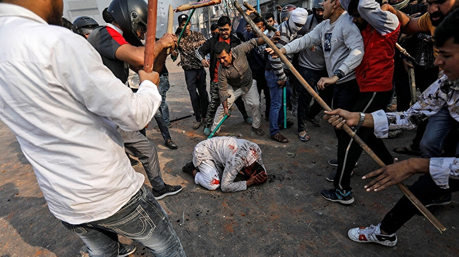 Yasayı destekleyen Hindular bir Müslümanı sopalarla döverken görülüyor.