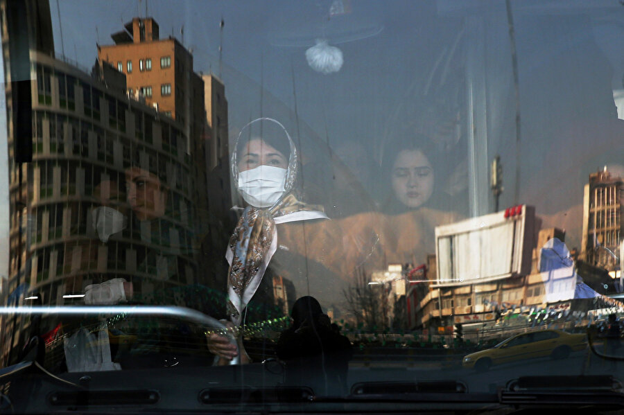 Tahran'da bir otobüste maske kullanan yolcular