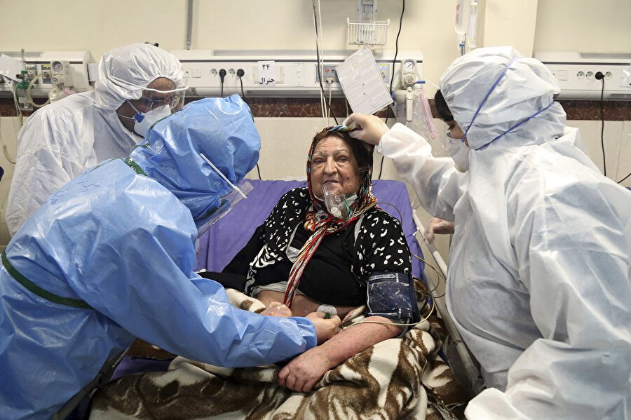 Koronavirüsle mücadele eden bir hastaya müdahale eden İranlı hekimler.