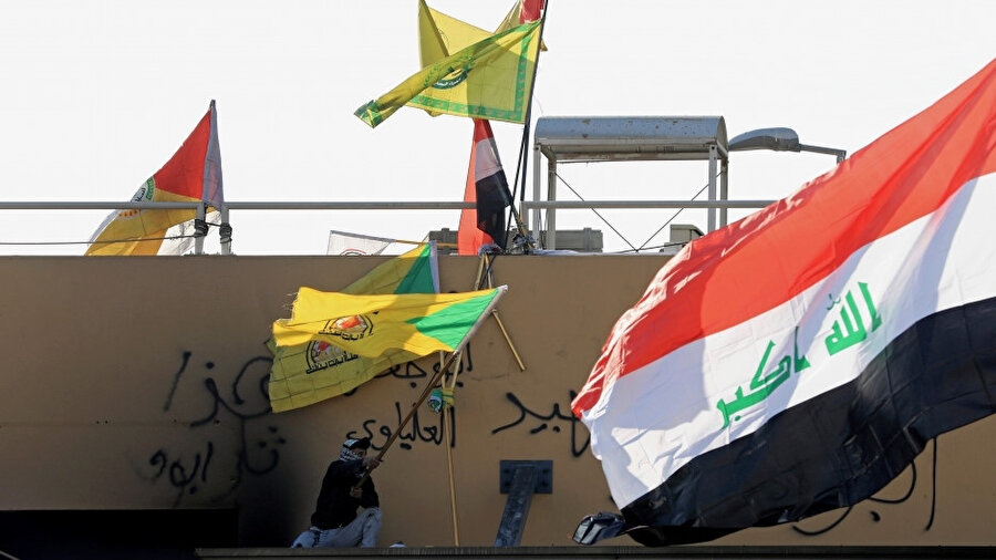 Irak’taki ABD elçiliği önünde Ketaib Hizbullah bayrağı sallayan bir Haşdi Şabi mensubu.