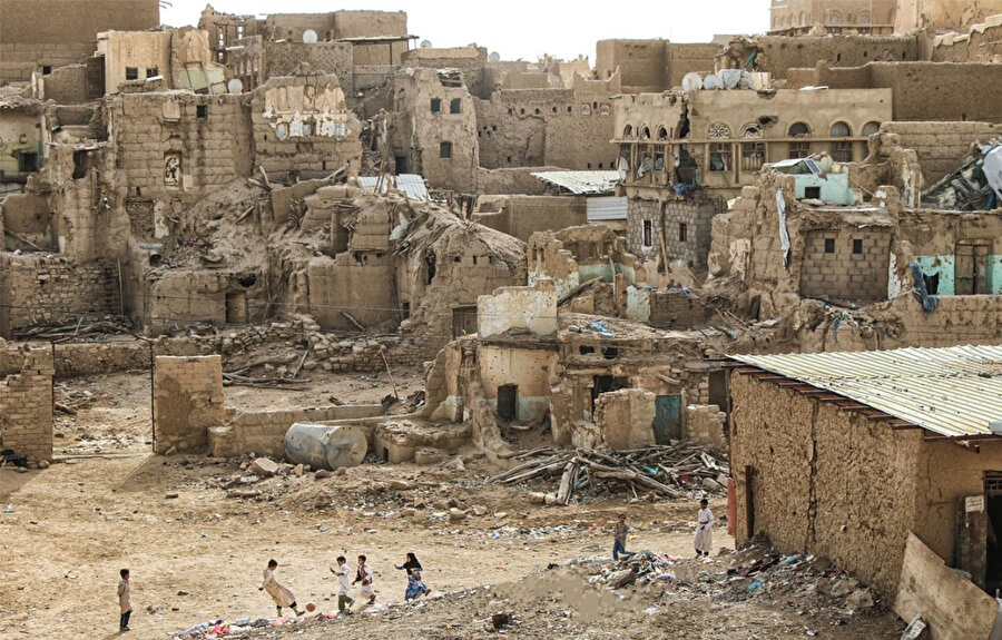 Savaşın ve sefaletin hüküm sürdüğü Yemen'de yıkılan evlerin arasında futbol oynayan çocuklar.