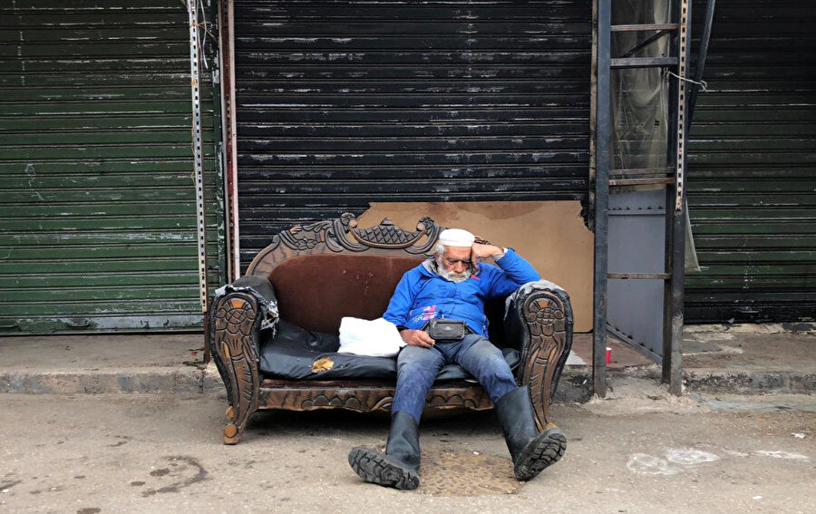 Koronavirüsle (Kovid-19) mücadele uygulamaları nedeniyle kapanan bir dükkanın önündeki koltukta uyuyan bir Lübnanlı. 