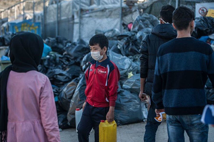 Yunanistan'daki kapasitesinin üzerinde binlerce kişiyi barındıran kamplarda maskeyle korunmaya çalışan mülteciler.