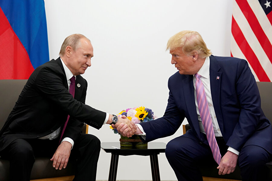Rusya Devlet Başkanı Vladimir Putin ve ABD Başkanı Donald Trump el sıkışırken görünüyor.