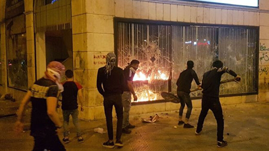 Yoldan söktükleri trafik levhaları ile banka şubelerine zarar veren göstericiler şubeleri ateşe verdi.