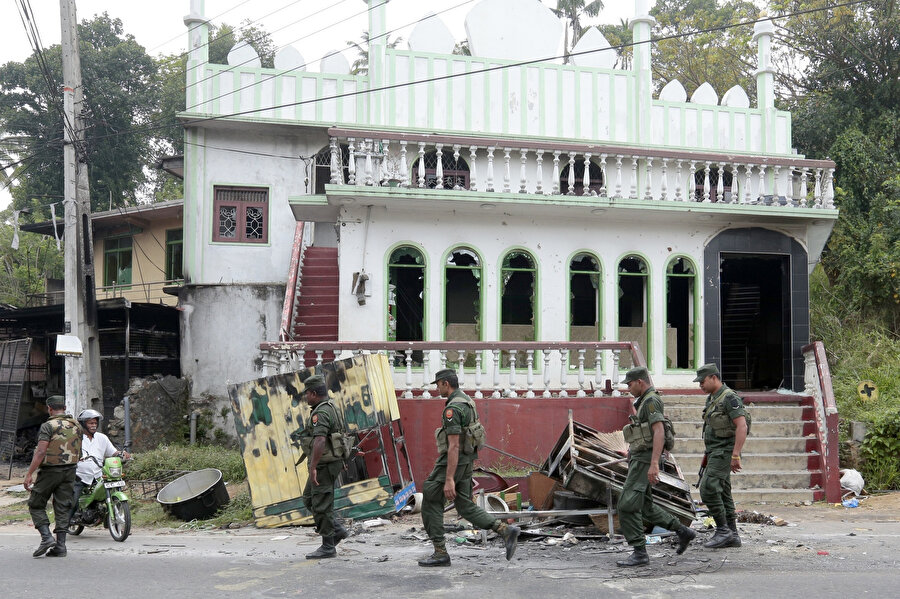 Sri Lankalı askeri yetkililer, olaylar sırasında saldırıya uğrayan caminin önünden geçerken görülüyor.